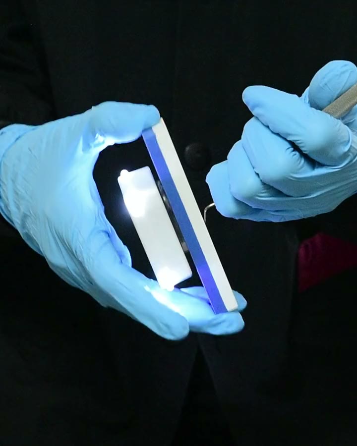 Gloved hands holding the ErgoSharp guide on a sharpening stone